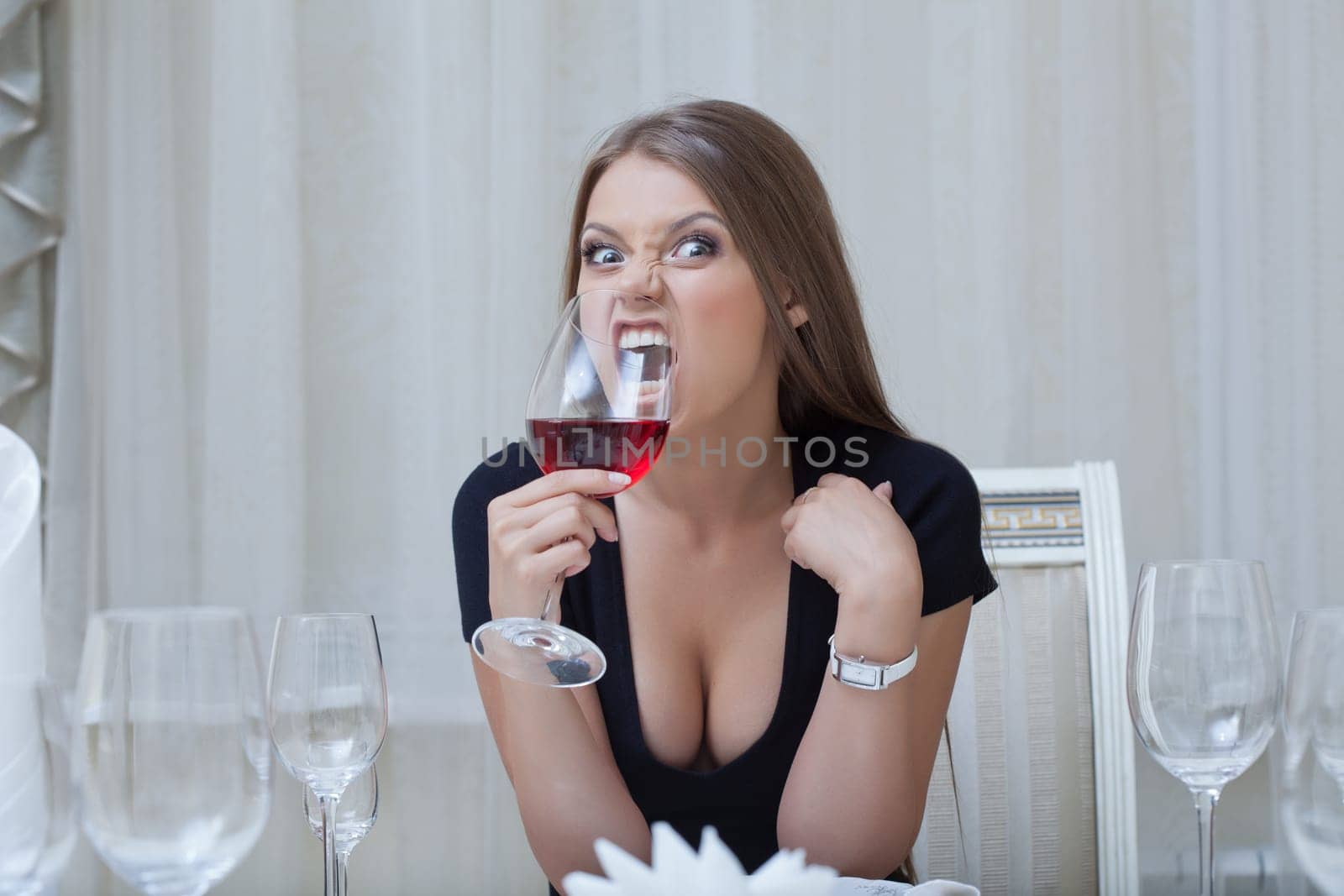 Image of pretty funny girl biting glass of wine, close-up