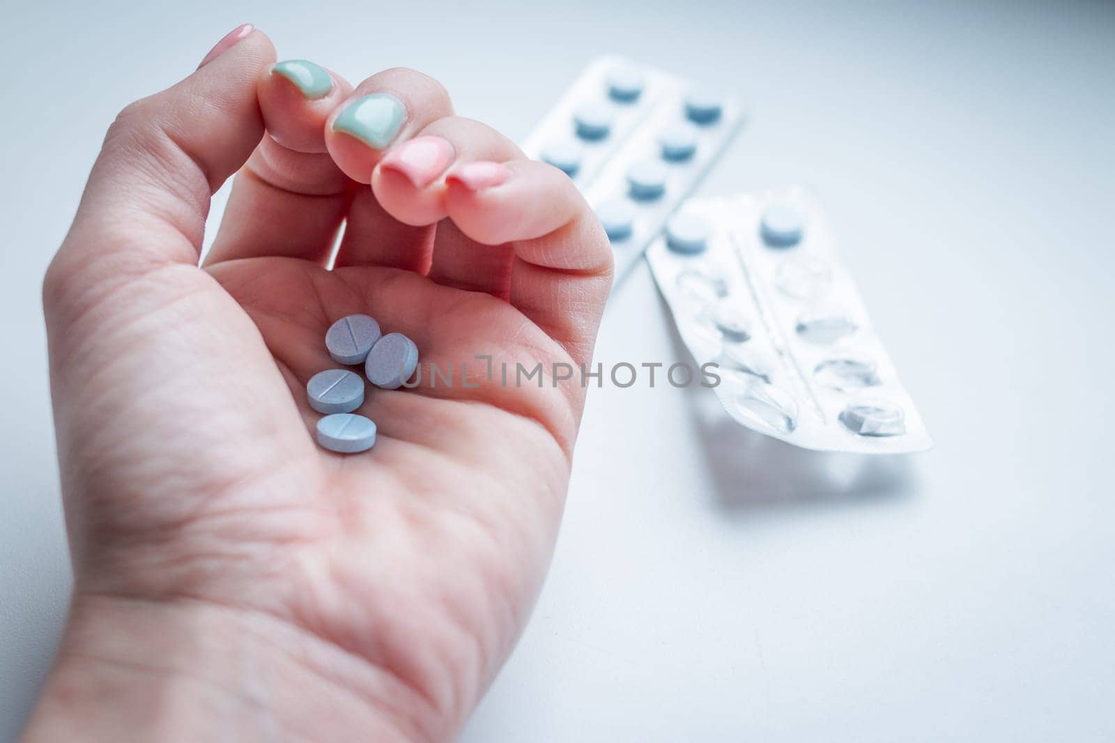 Pills, tablets and drugs heap in doctor's hand on blue background