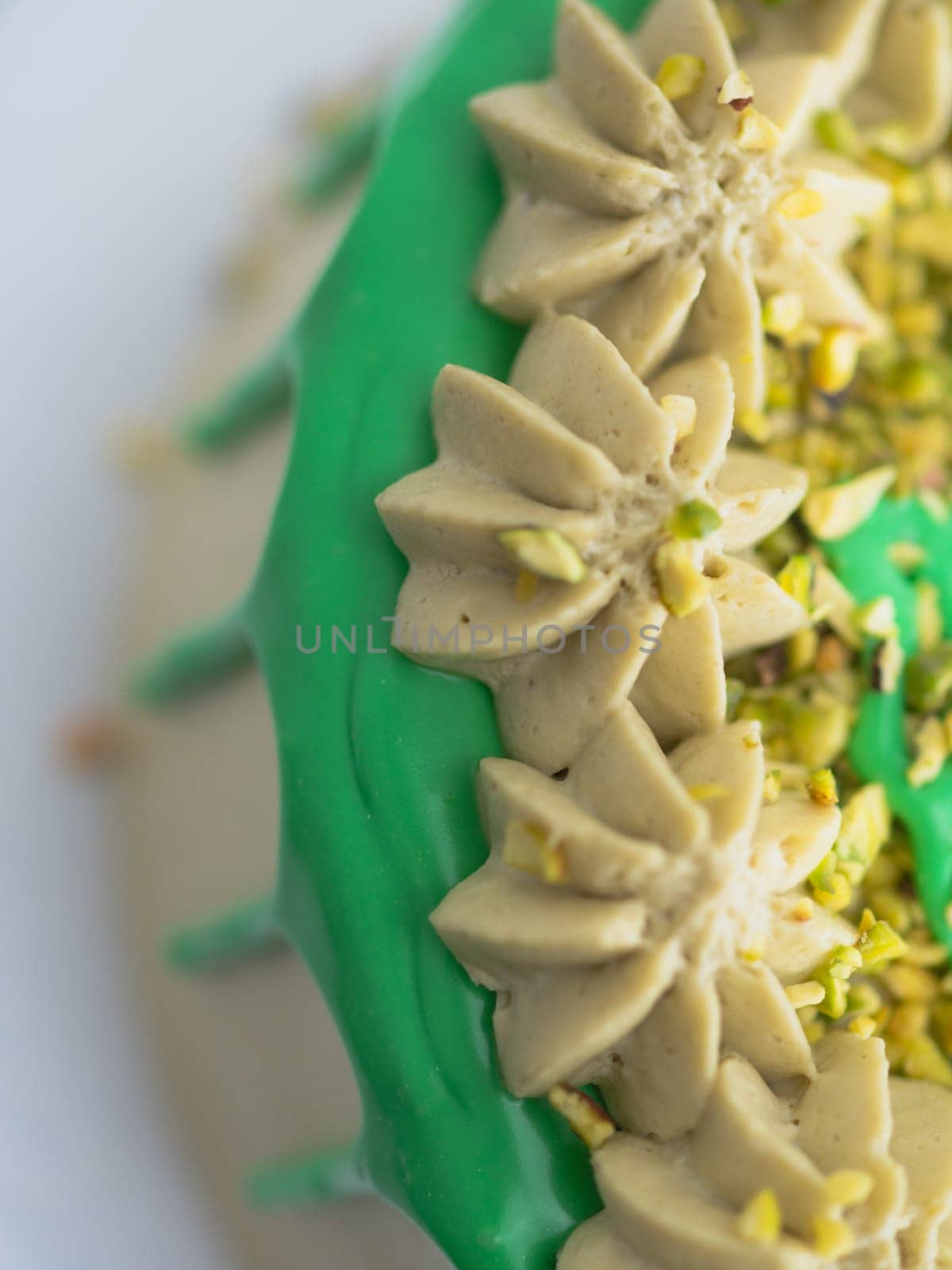 studio shot of green pistachio frosted dripped icing cup cake