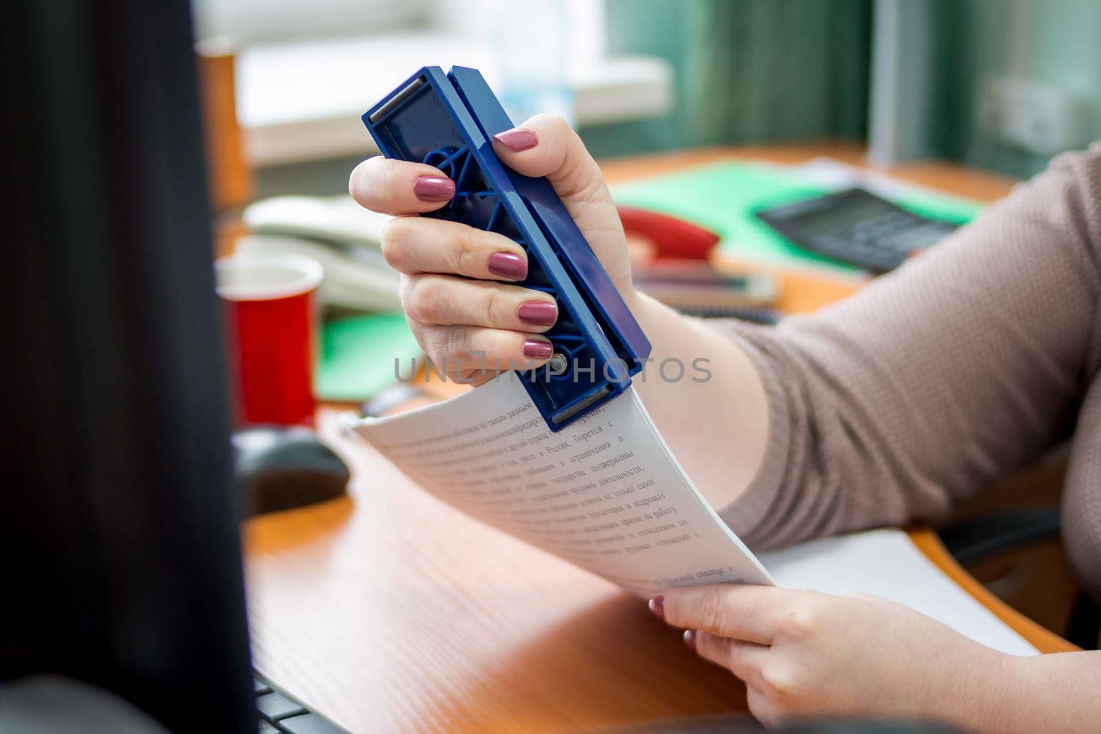 Detail of female hands holding a stapler and filling it with the staples. Focus on the fingers and the staples