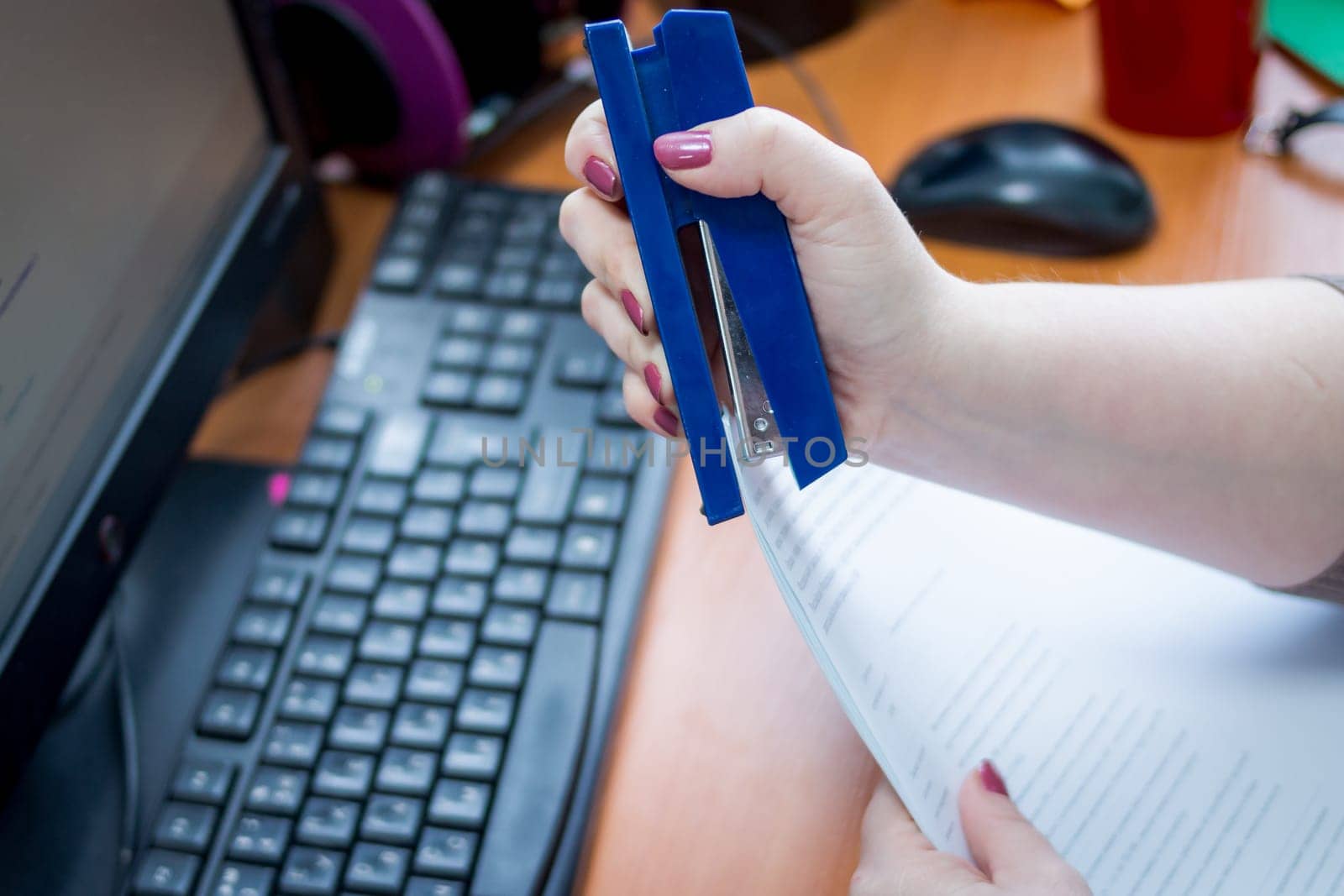 Detail of female hands holding a stapler and filling it with the staples. Focus on the fingers and the staples