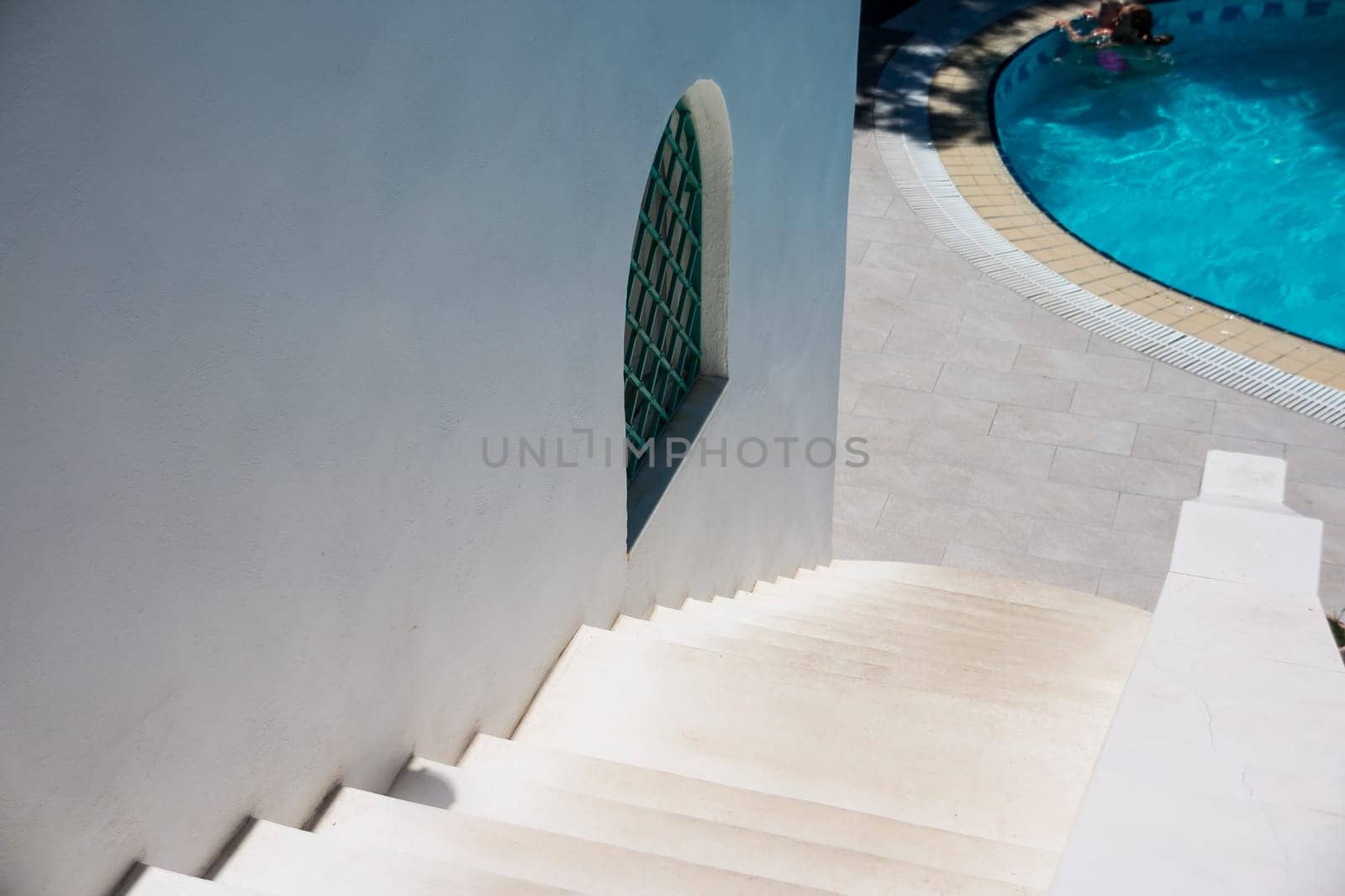 white stone stairs, ladder outside on sunny day. white house with swimming pool.