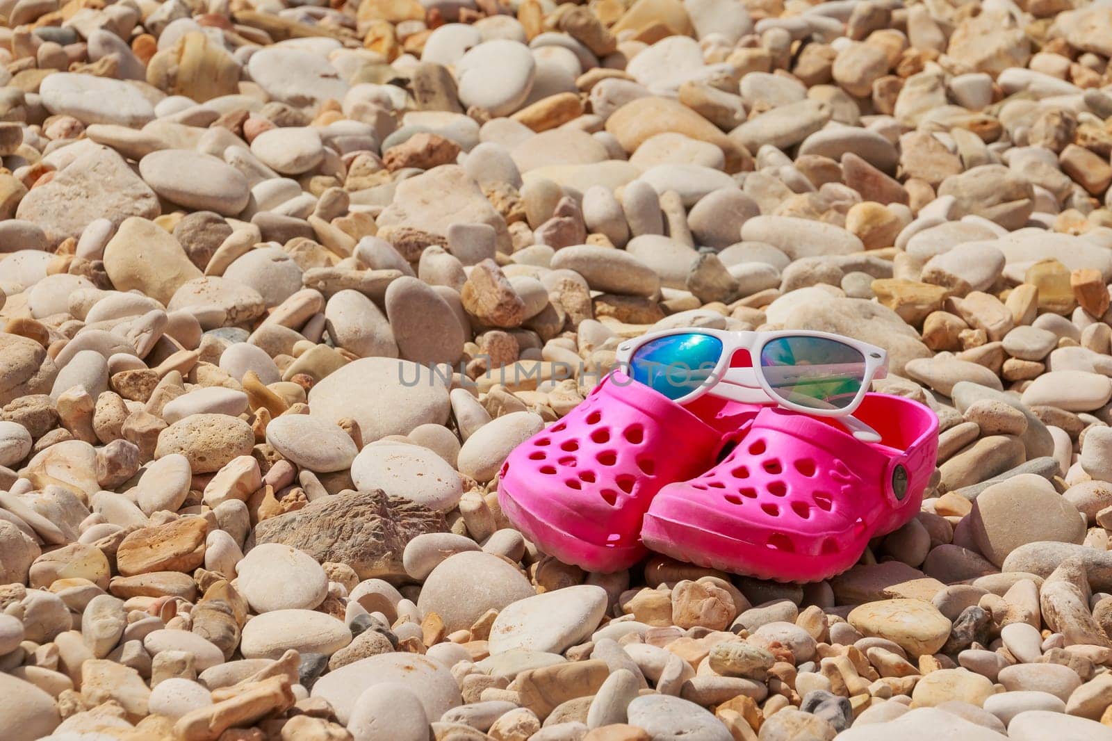 Colorful kids sandals on a pebble beach