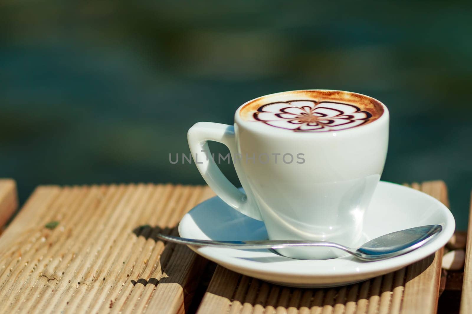 Cup of art latte on a cappuccino coffee isolated outside, on the beach.Morning coffee. white cup of latte hot coffee with leaf