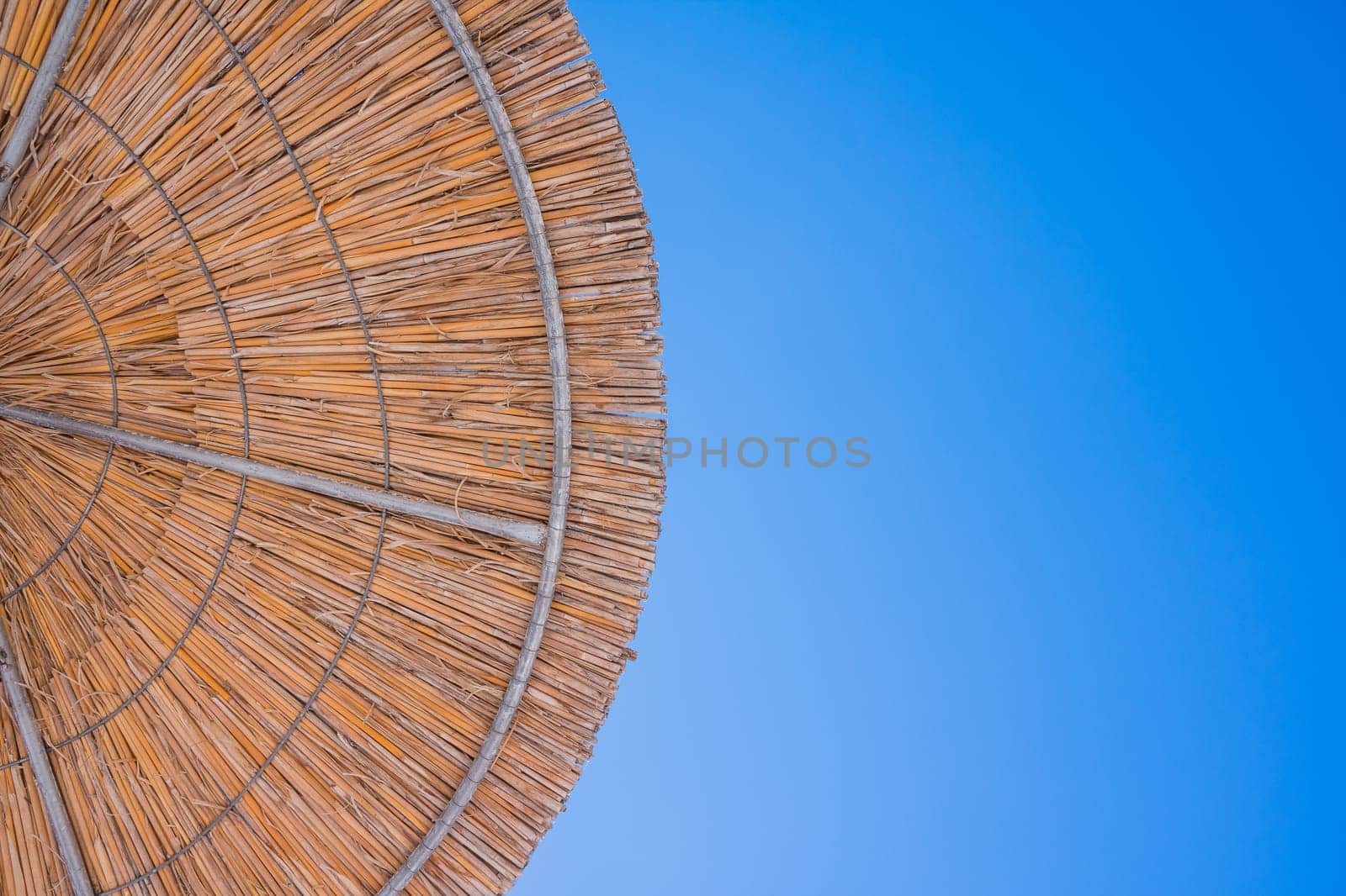 Straw roof of sun umbrella against the blue sky. Vacation topic.