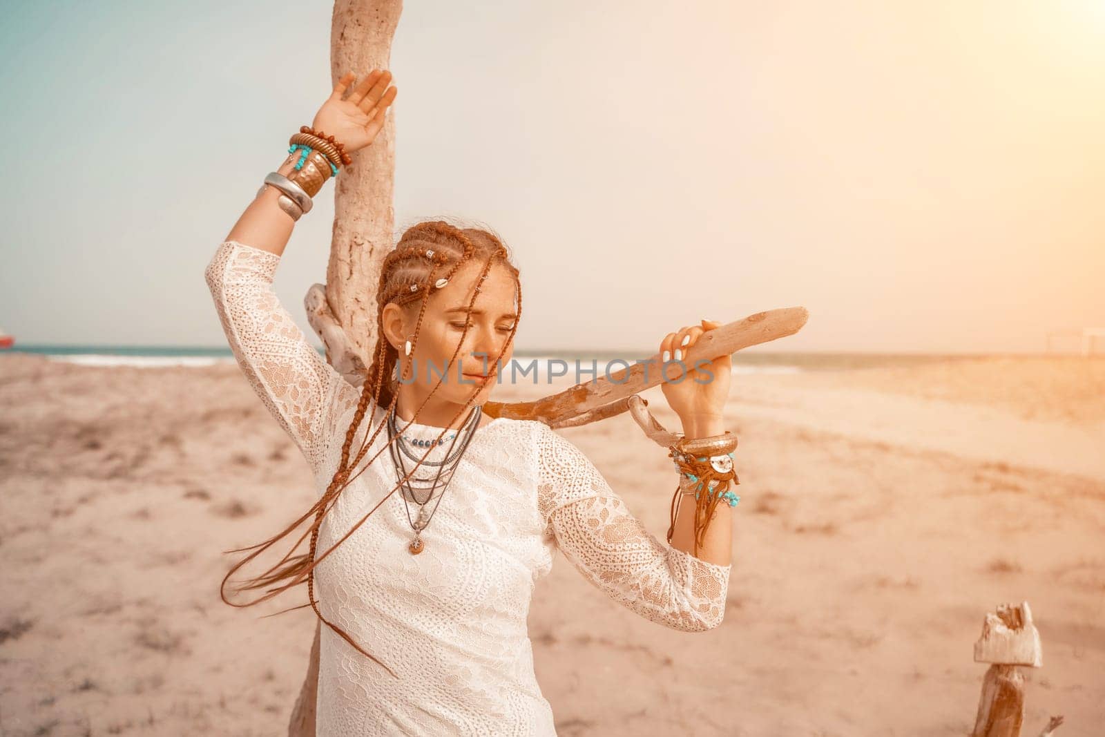 woman sea white dress. Model in boho style in a white long dress and silver jewelry on the beach. Her hair is braided, and there are many bracelets on her arms