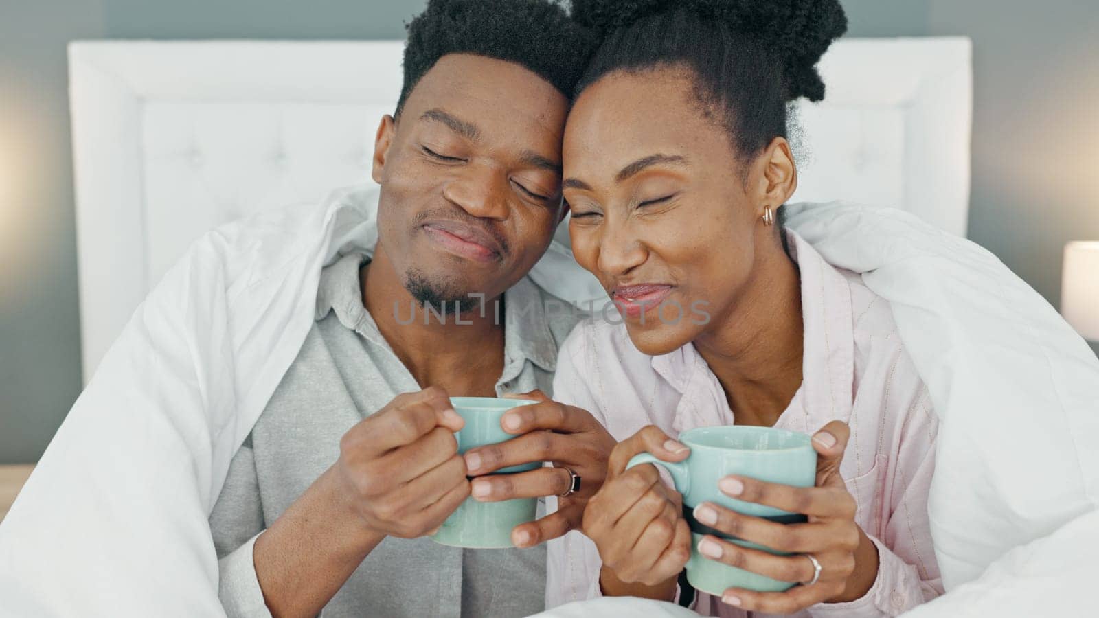 Coffee, bed and couple with a man and woman in the bedroom to relax in their home together. Drink, tea and romance with a young male and female sitting in their house in the morning over a weekend.