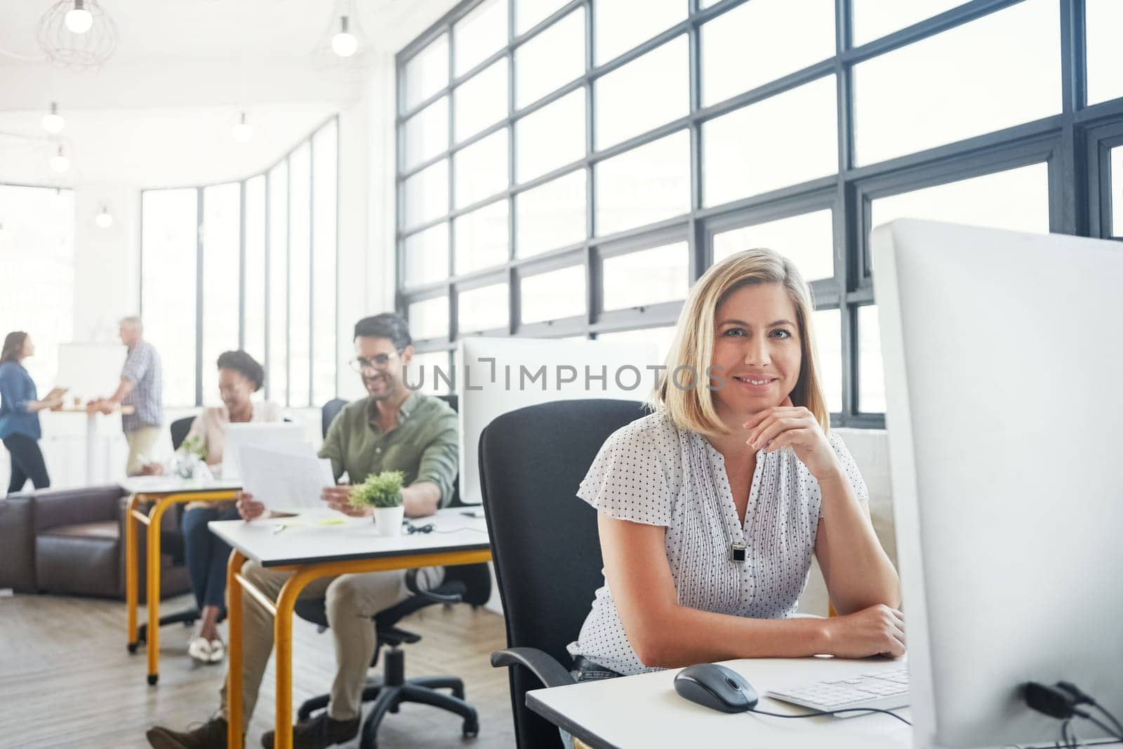 Theres some tools that can make life easy for designers. Portrait of a young designer in an office with her colleagues in the background. by YuriArcurs