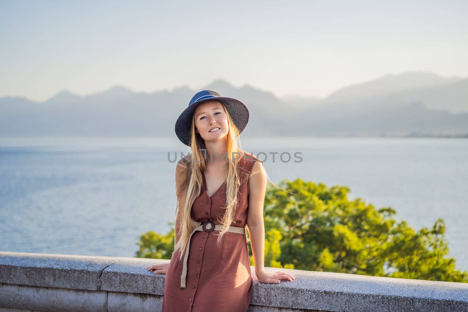 Happy woman tourist on background of Antalya sea and mountain views, sea in Turkey Antalya City. female tourist traveler discover interesting places and popular attractions and walks in the old city Kalechi of Antalya, Turkey. Turkiye.
