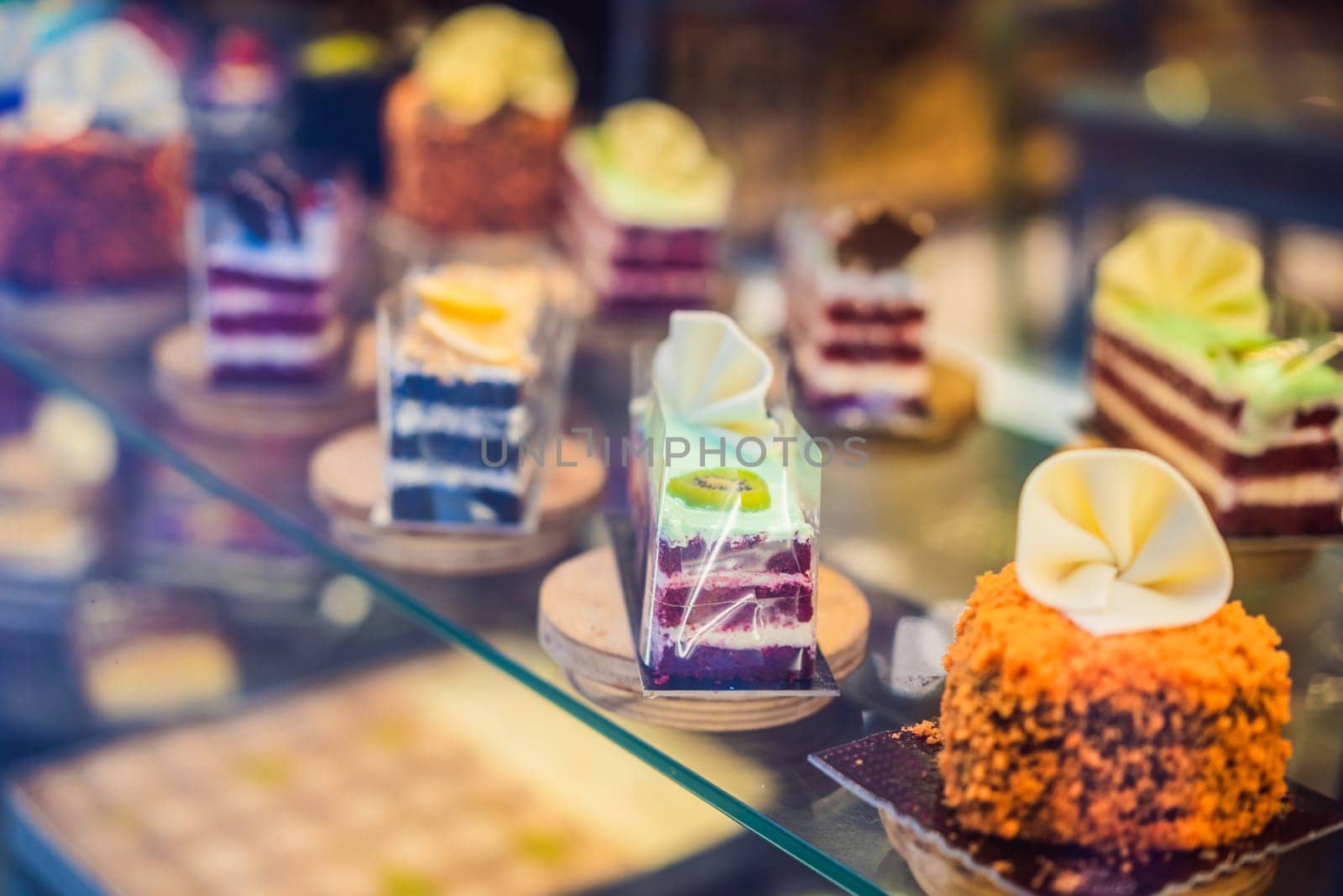 Different types of cakes in pastry shop glass display.