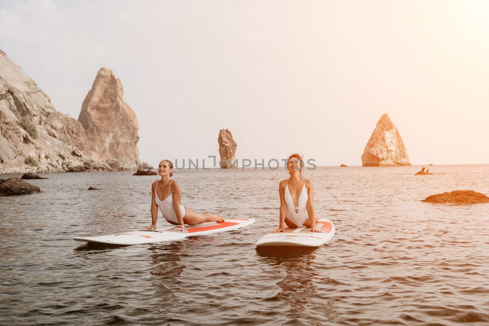 Woman sup yoga. Happy sporty woman practising yoga pilates on paddle sup surfboard. Female stretching doing workout on sea water. Modern individual female hipster outdoor summer sport activity. by panophotograph