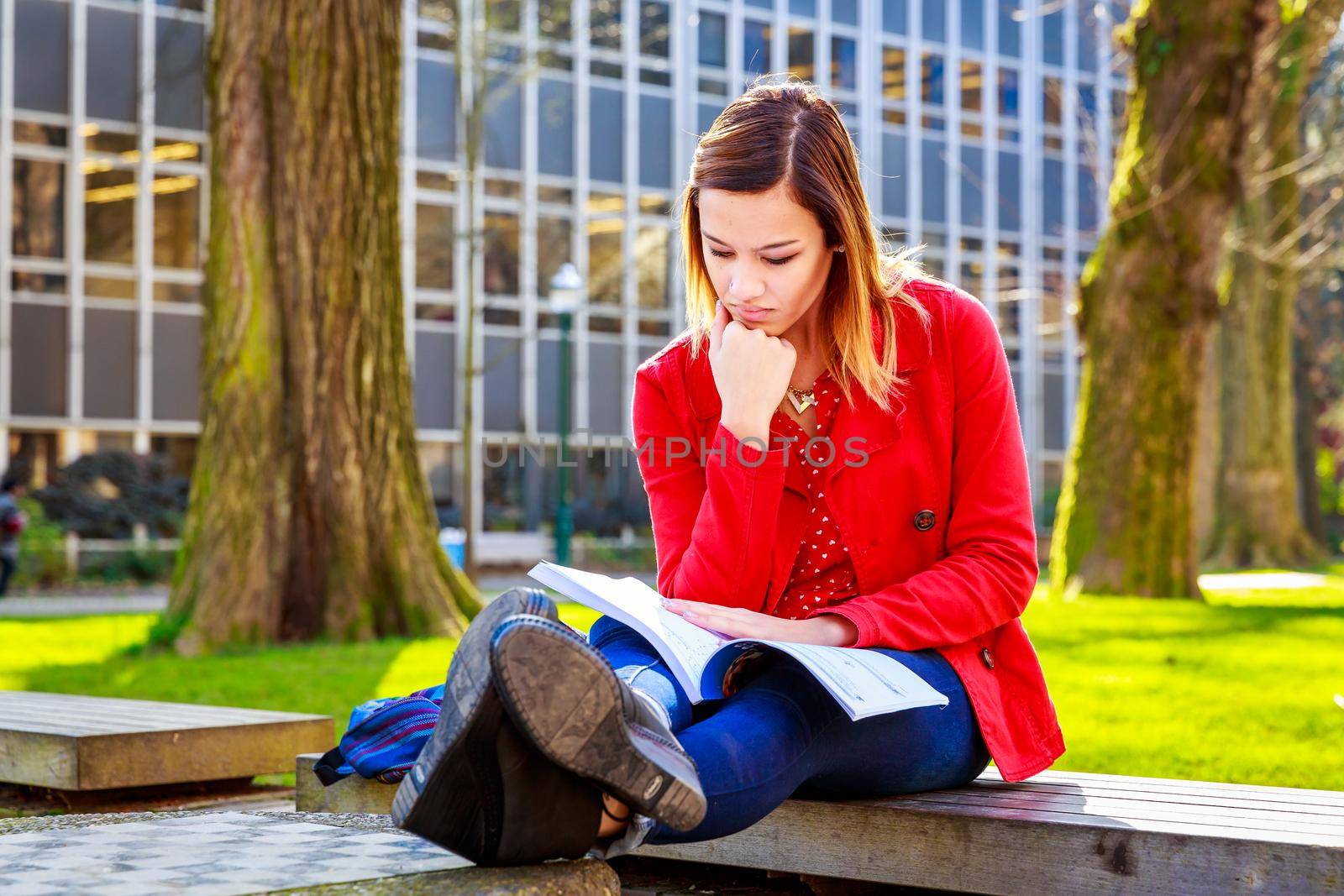 A young female college student study books outside of library.