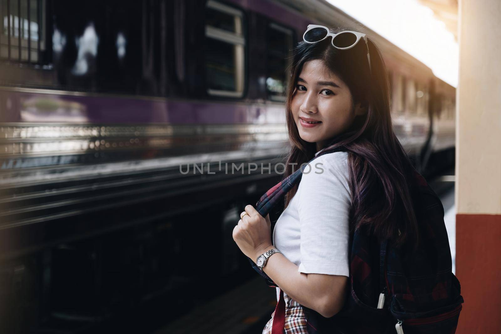 Image of a woman with a rucksack standing at a train station waiting to board a train. concept of solo travel. by itchaznong