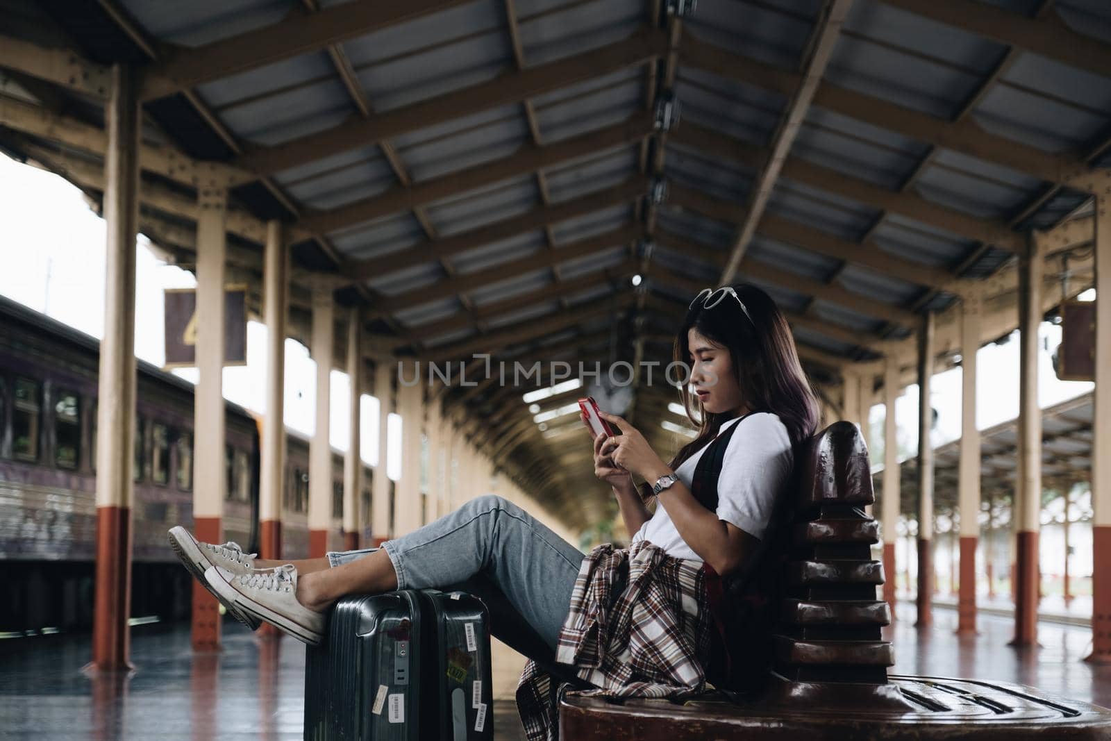 Image of A traveler checking message from her friend and waiting at train station. Travel concept.