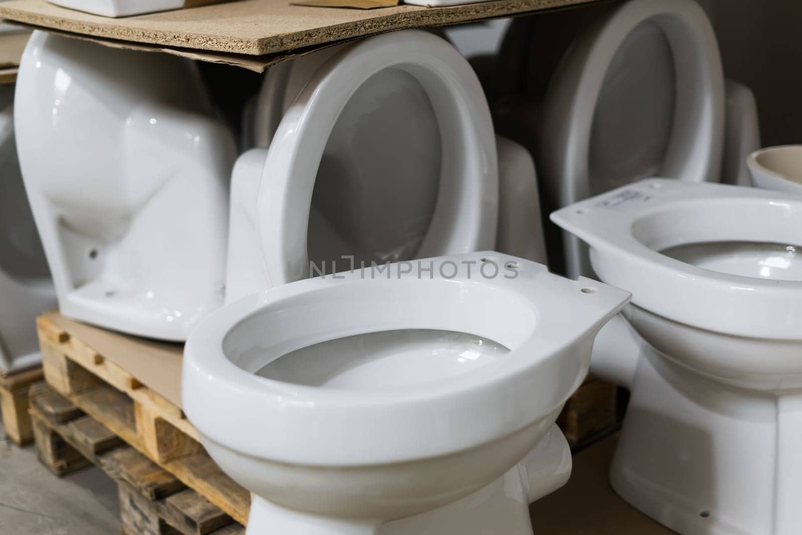 Lot of white toilets in hardware store, plumbing department by Zelenin