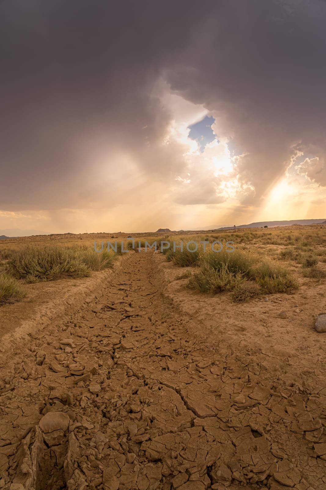 View of Bardenas Reales with stormy sky and dry and cracked ground in Spain.