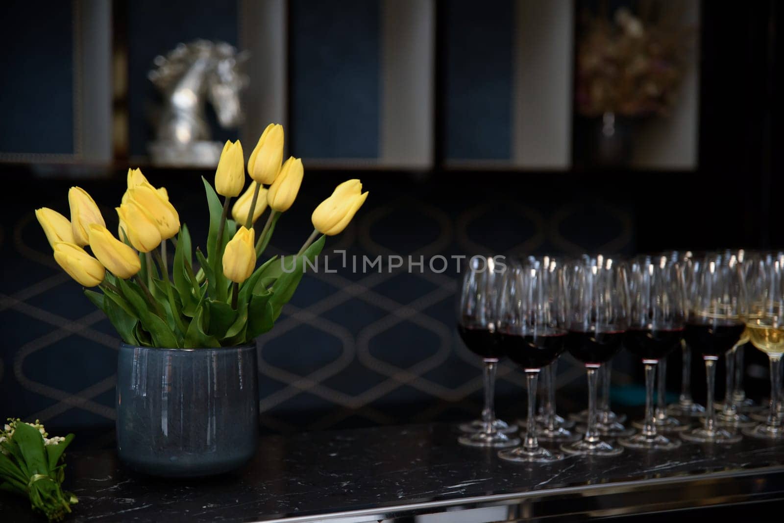 Beautiful spring bouquet of yellow tulips in a gray vase. vase with tulips in a dark room.