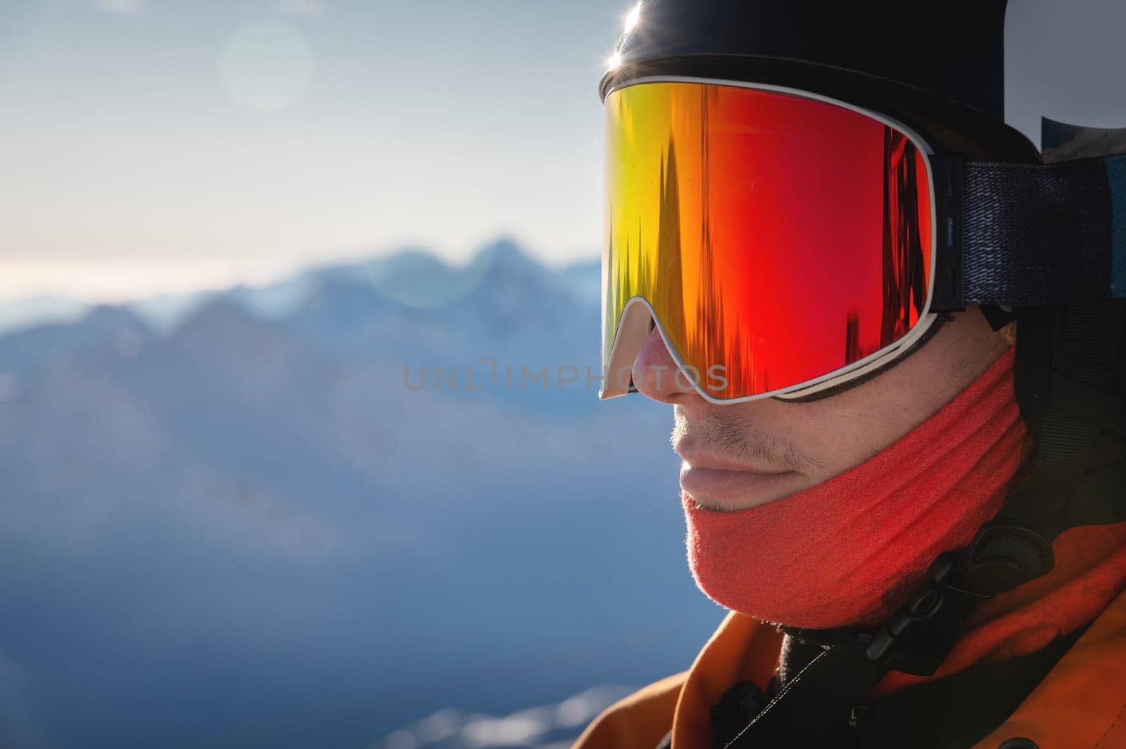 Close-up portrait of a guy holding skis in winter, he is wearing sportswear such as a helmet and sunglasses. winter, freedom, nature, sports, competitions. winter holidays in the alps, travel, hiking.