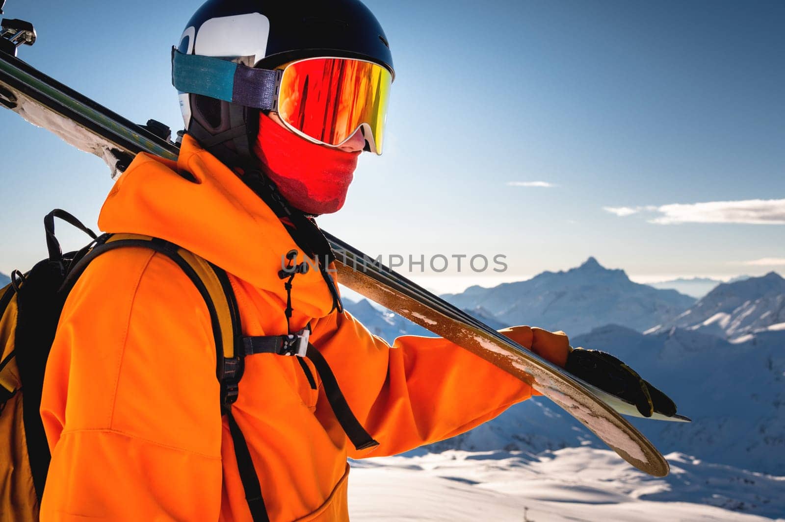 shot of a skier standing on top of a mountain with skis on his shoulder on a sunny winter day, sunlight, outdoor recreation, skiing, lifestyle, downhill sport concept by yanik88