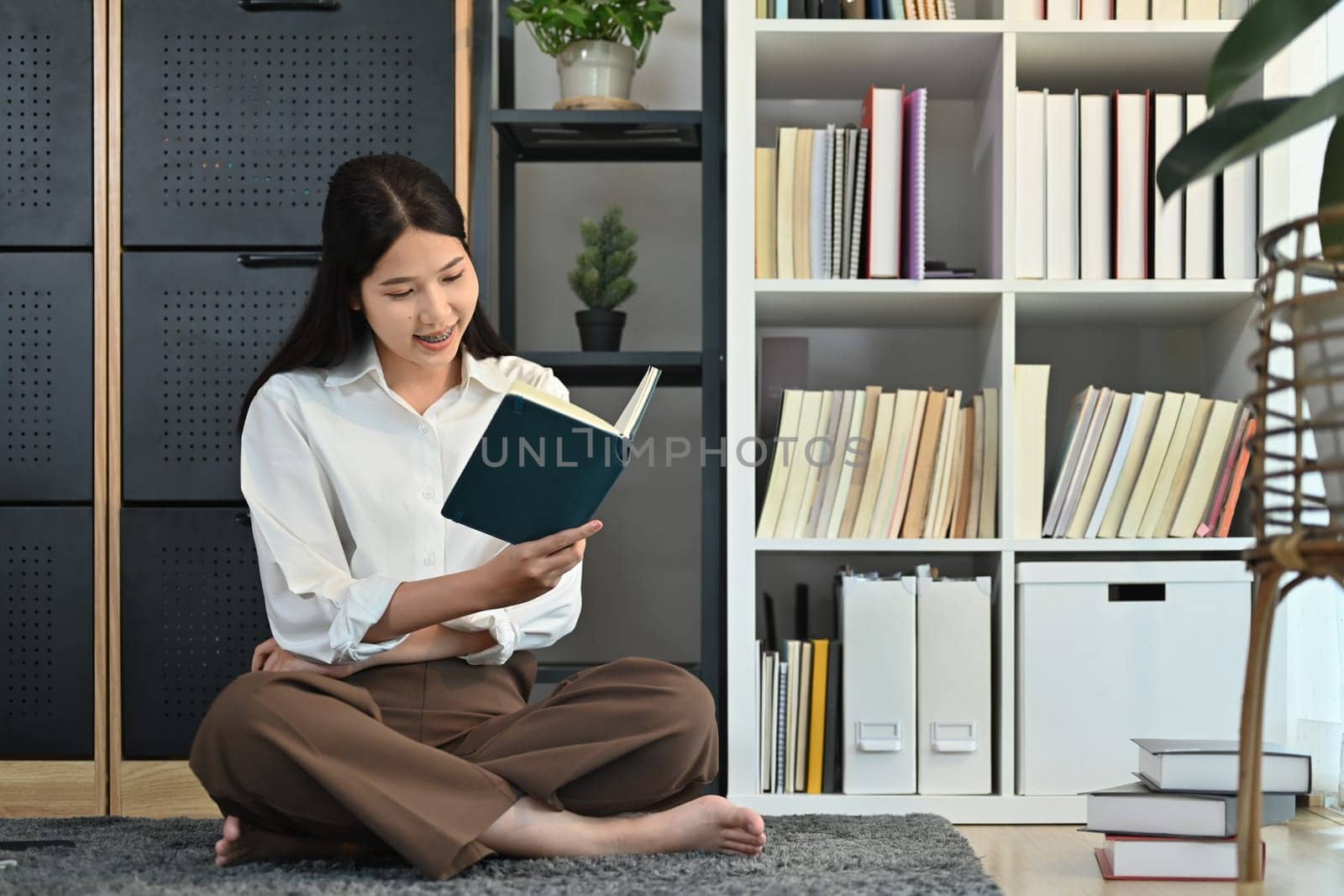 Portrait of happy millennial woman reading interesting book, enjoying leisure weekend time with favorite novel alone at home.