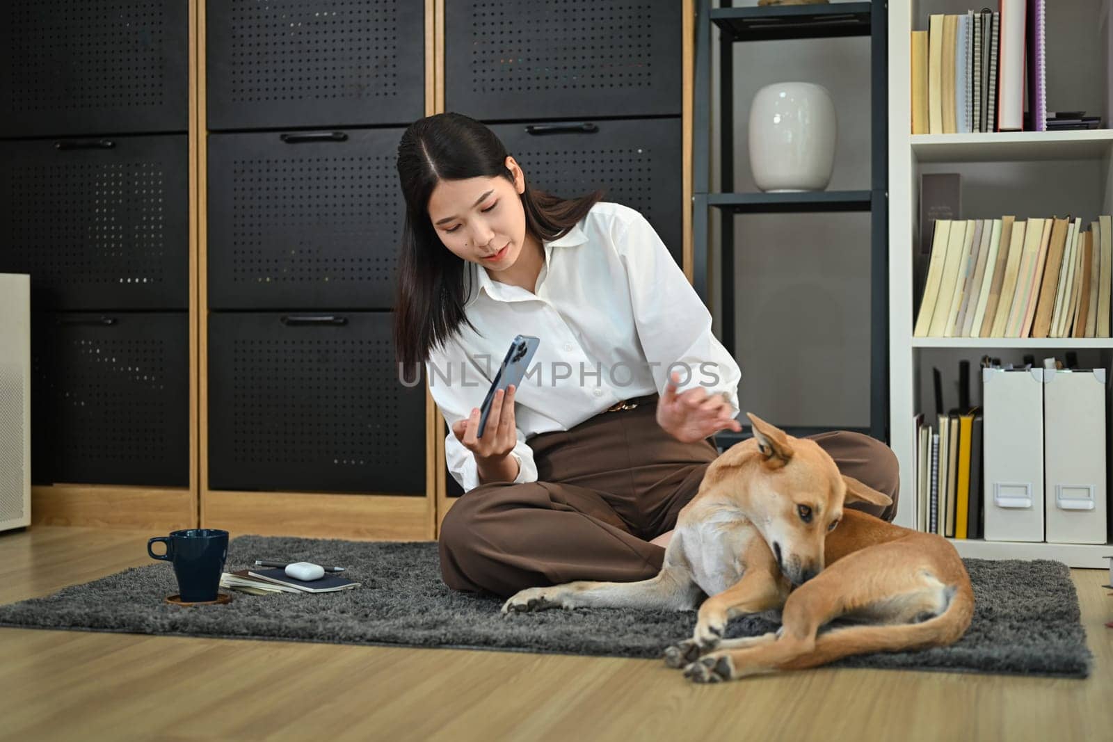 Happy young woman taking pictures of her dog on smartphone. Technology, people and animals concept by prathanchorruangsak