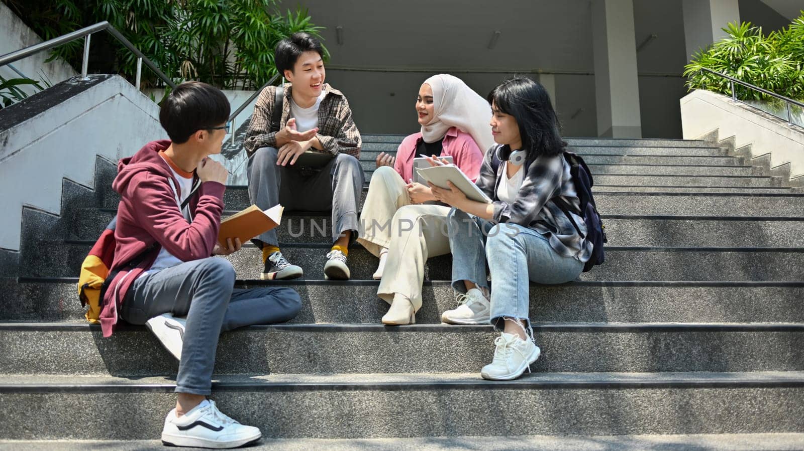 Group of college students spending time together on campus and talking during break. Friendship and lifestyle concepts.