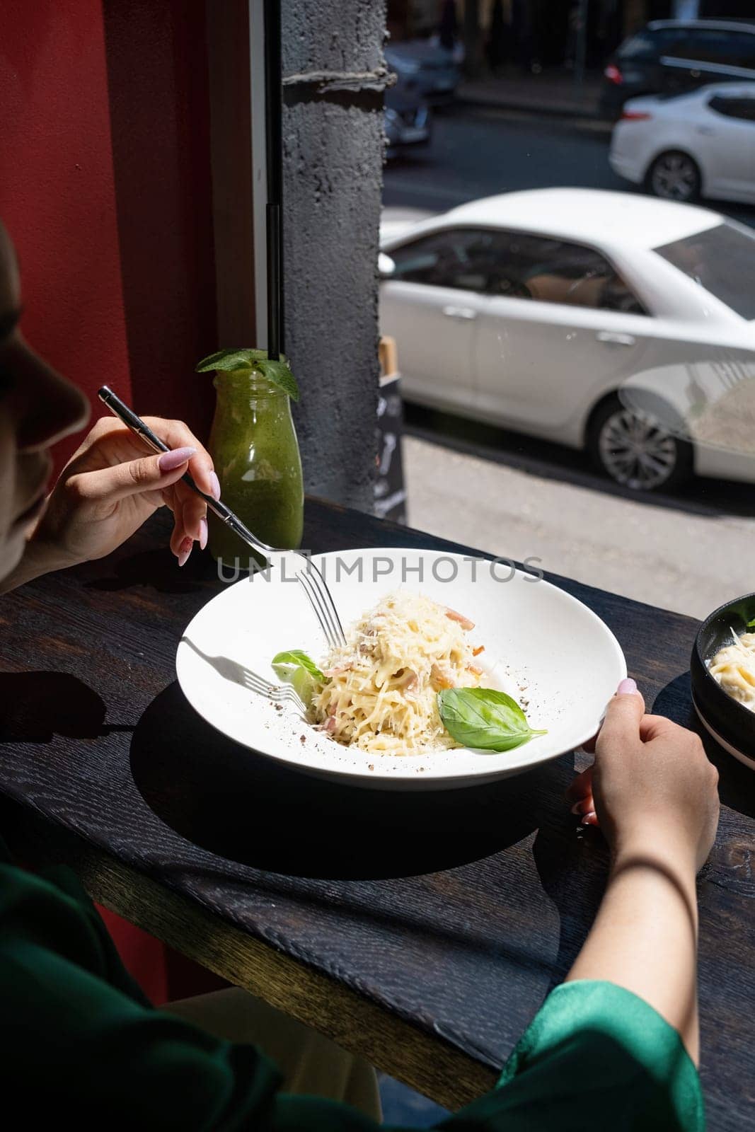 Woman eating italian pasta sitting at the cafe counter looking to the window, having lunch. Street background