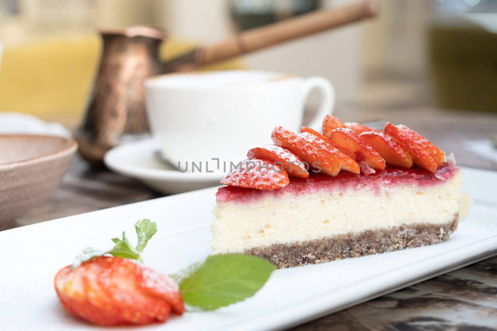 Piece of delicious cheesecake with berries on real cafe table close up. Cup of coffee on the background