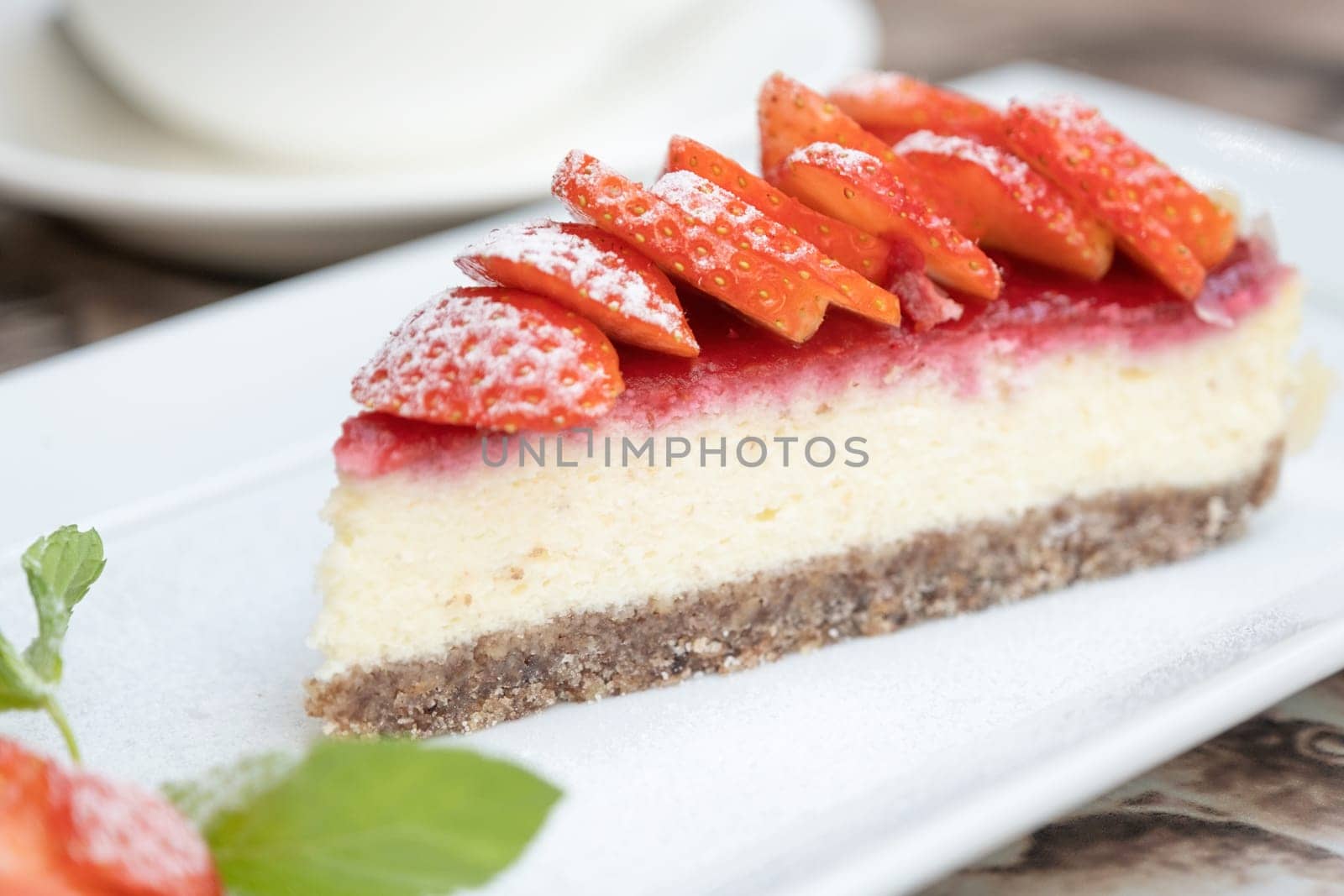 Piece of delicious cheesecake with berries on real cafe table close up. Cup of coffee on the background