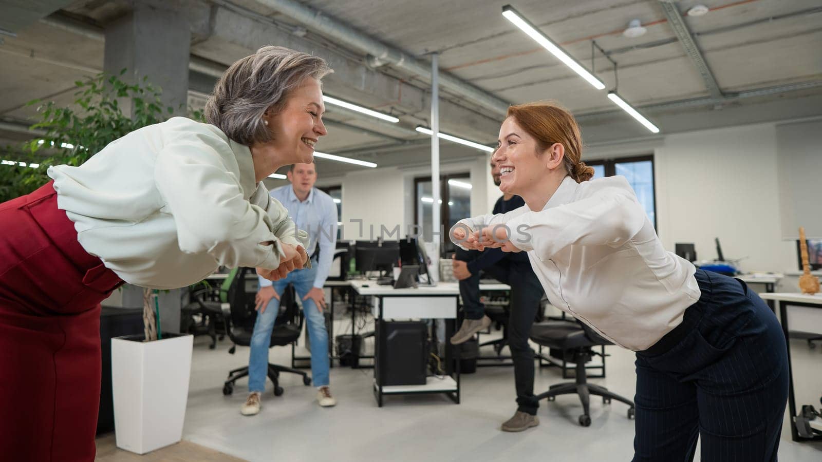 Four office workers warm up during a break. Employees do fitness exercises at the workplace