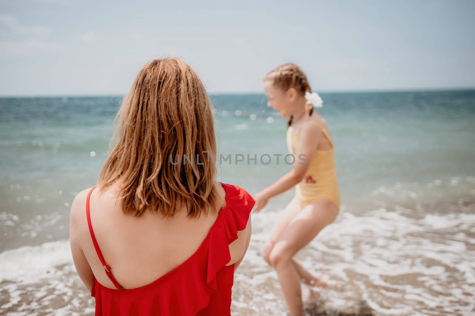 Happy loving family mother and daughter having fun together on the beach. Mum playing with her kid in holiday vacation next to the ocean - Family lifestyle and love concept.