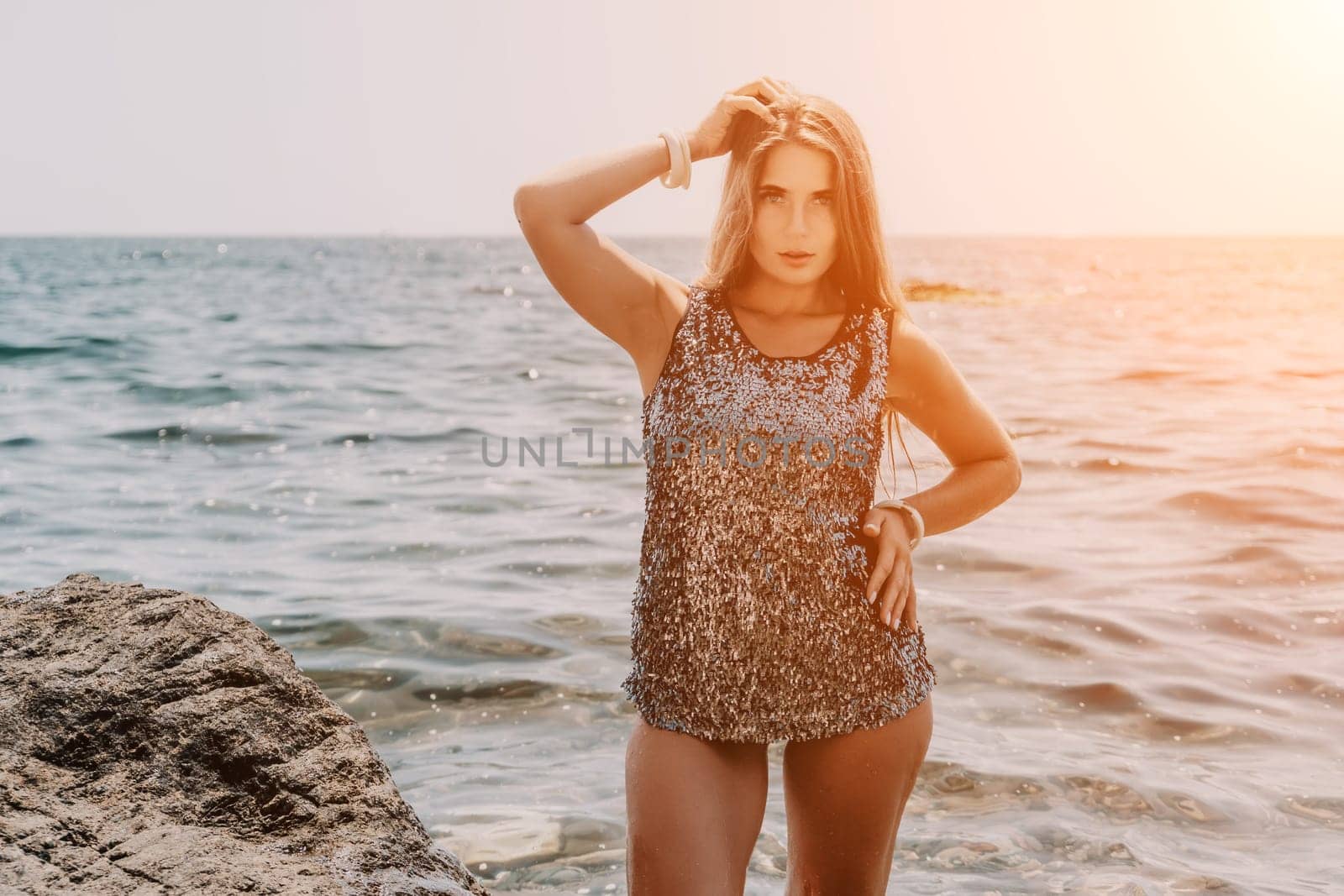 Woman travel sea. Young Happy woman in a long red dress posing on a beach near the sea on background of volcanic rocks, like in Iceland, sharing travel adventure journey