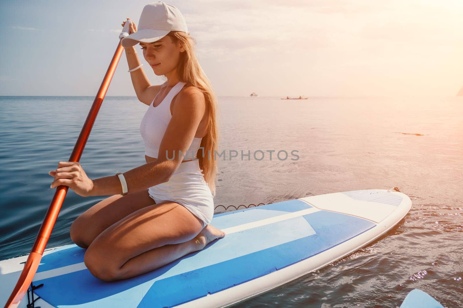 Close up shot of beautiful young caucasian woman with black hair and freckles looking at camera and smiling. Cute woman portrait in a pink bikini posing on a volcanic rock high above the sea