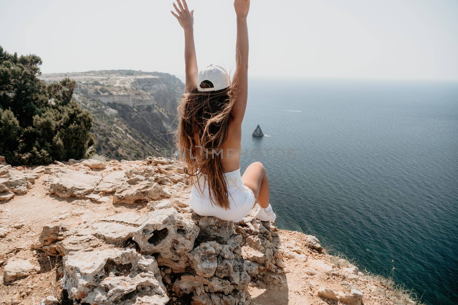 Woman travel sea. Young Happy woman in a long red dress posing on a beach near the sea on background of volcanic rocks, like in Iceland, sharing travel adventure journey