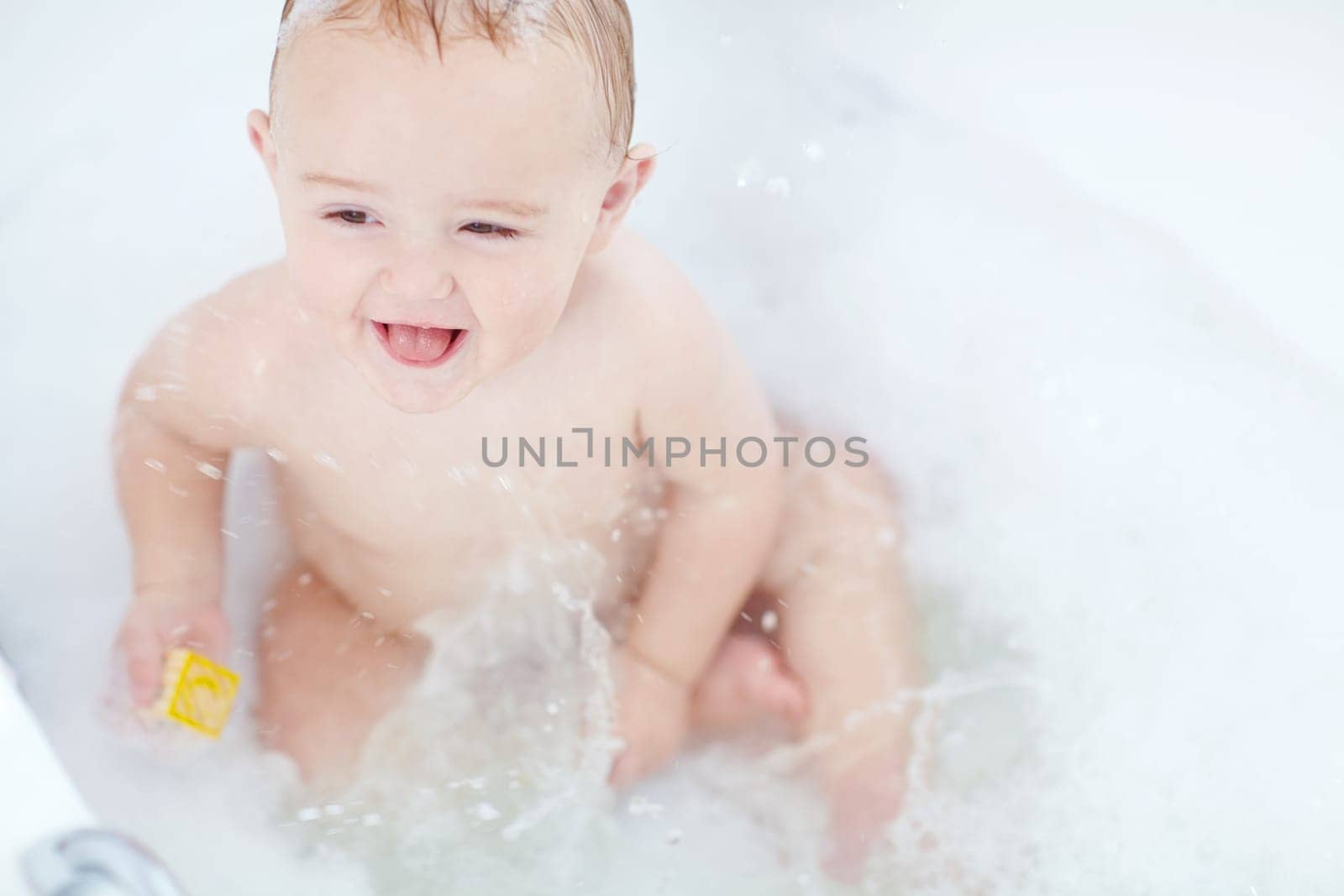 Splish splash. an adorable baby boy playing with a toy while bathing. by YuriArcurs