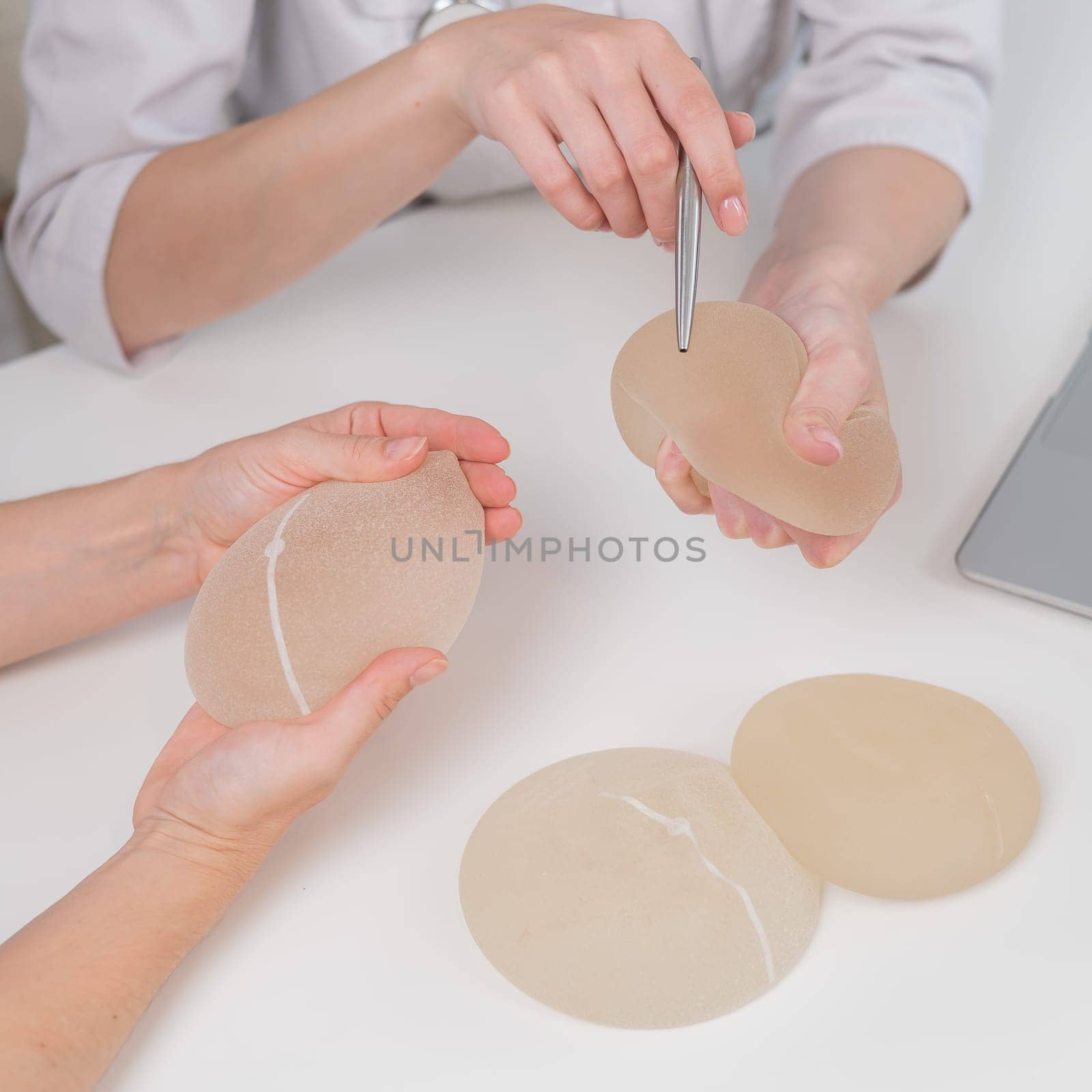 Caucasian woman and plastic surgeon touching and choosing breast implants