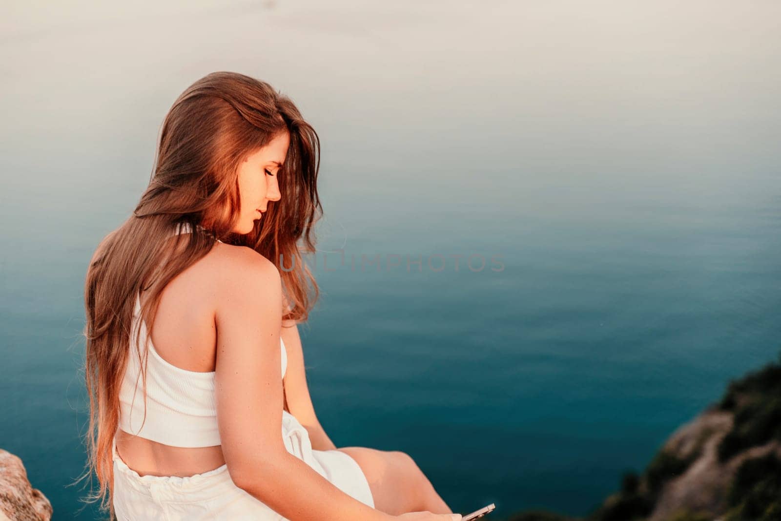 Portrait of a happy woman in a cap with long hair against the sea.