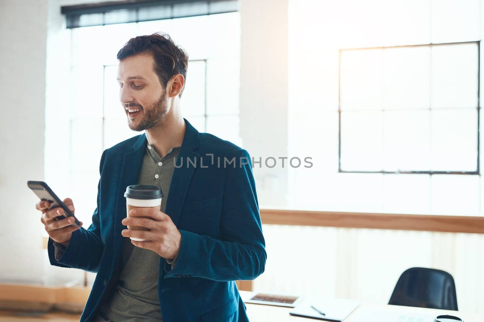 Communication is his key to success. a handsome young businessman using his cellphone while working in a modern office