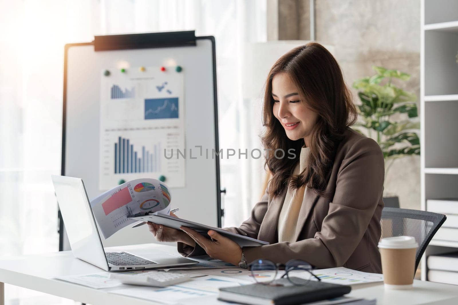 A female business is reviewing company financial documents, monthly financial statement summary from the finance department and growth.
