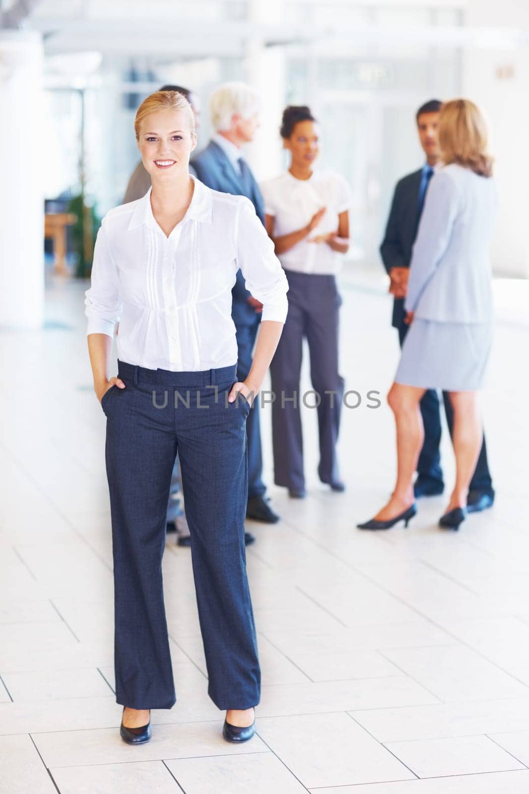 Smiling young executive with business people. Full length of young female executive standing with business people discussing in background. by YuriArcurs