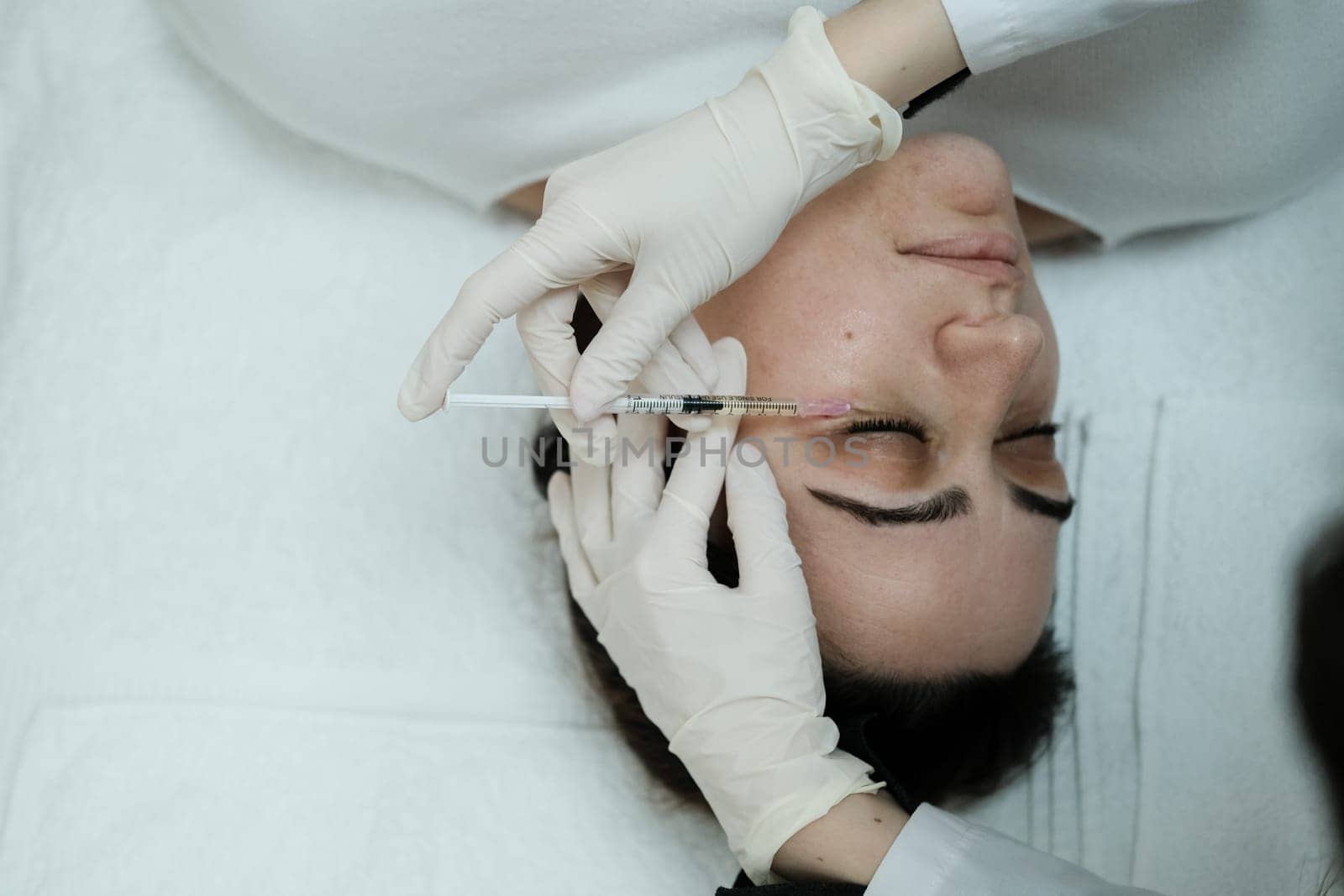 Cosmetologist applying eye mesotherapy to female patient by danjelaruci