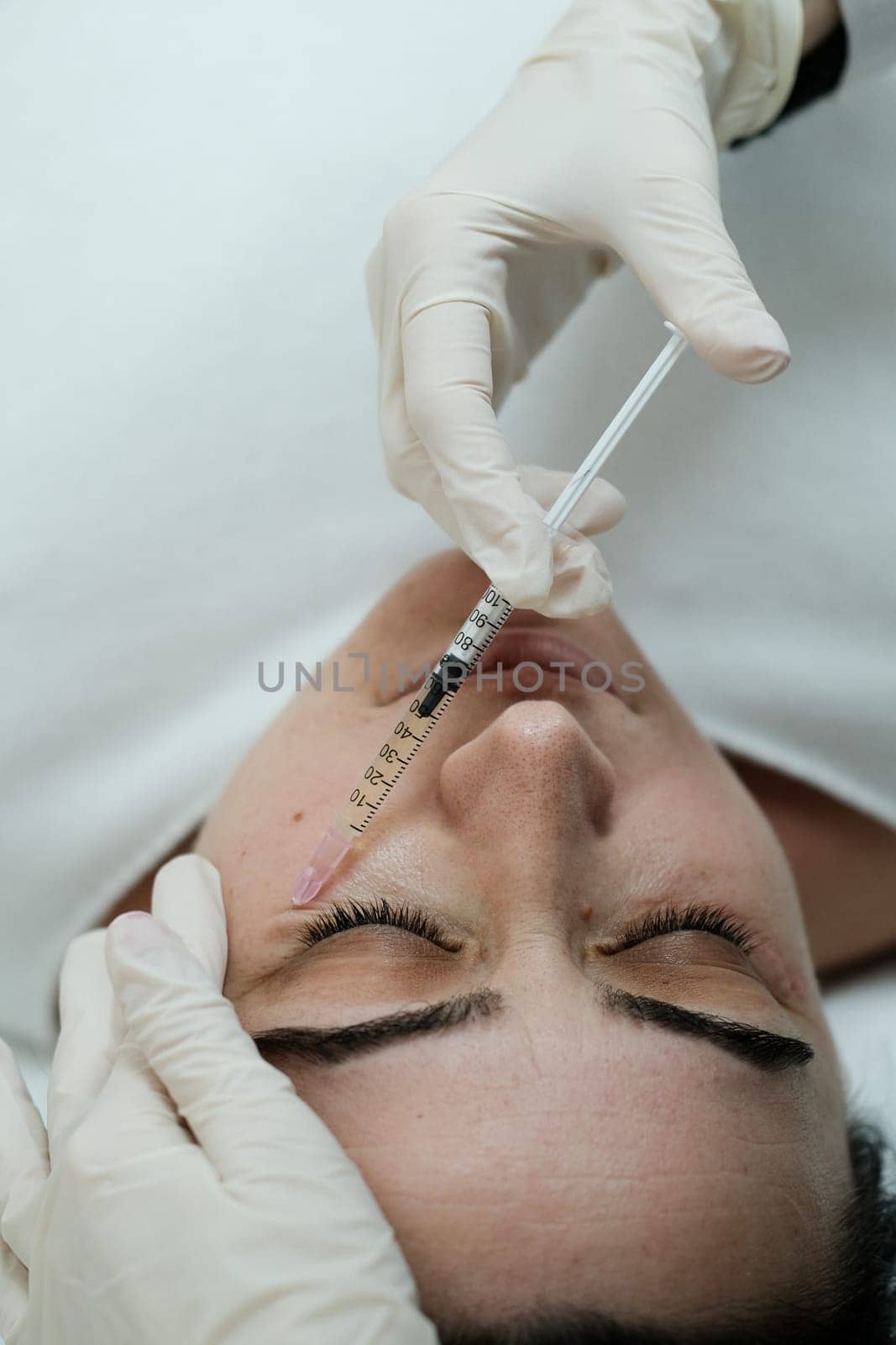 Cosmetologist applying eye mesotherapy to female patient by danjelaruci