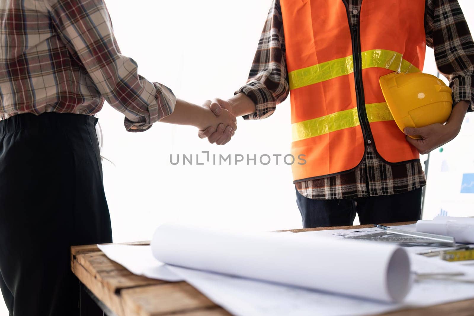 Architect and engineer construction workers shaking hands while working for teamwork after finish an agreement in the office construction site by nateemee
