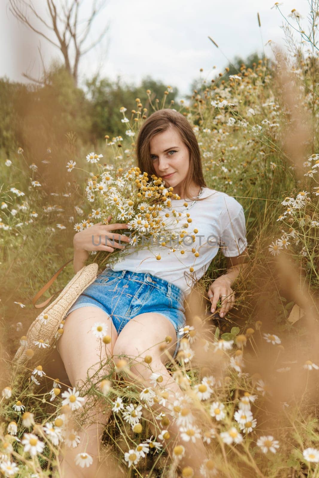 A beautiful woman in a straw hat walks in a field with purple flowers. A walk in nature in the lupin field.