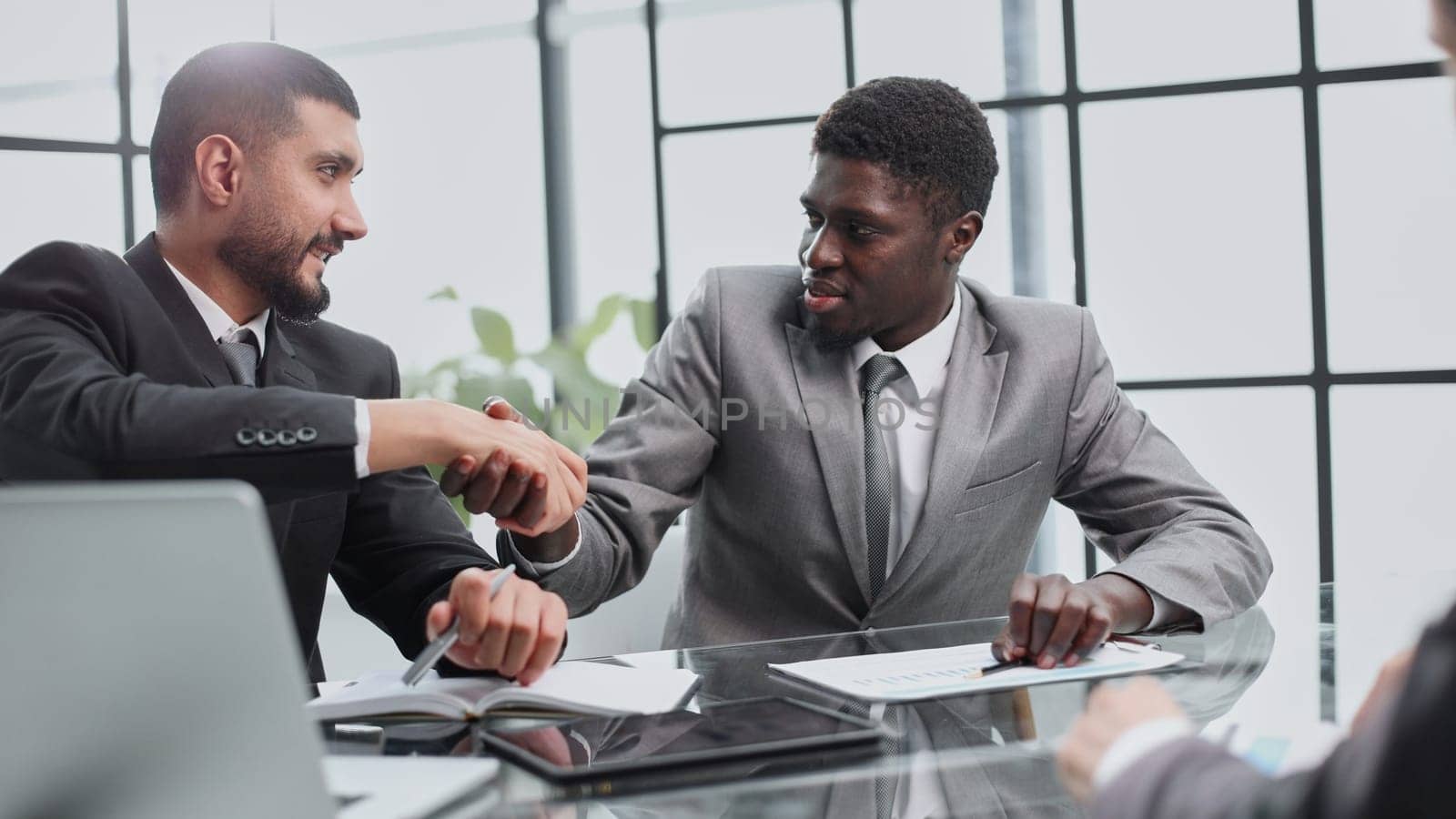 Top three men sitting at the desk and shaking hands