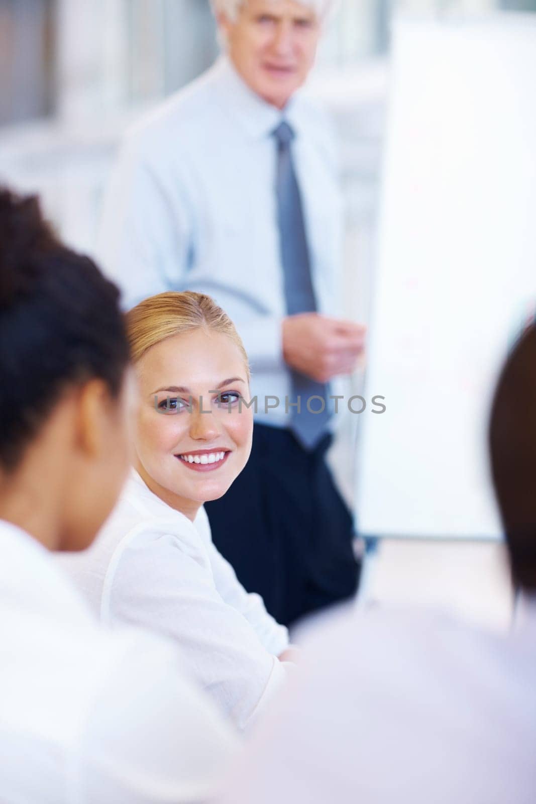 Pretty business woman with team in meeting. Portrait of pretty young business woman smiling with team in meeting. by YuriArcurs