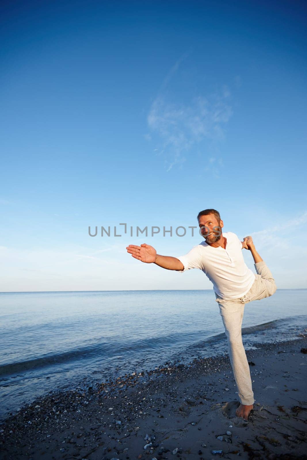 Yoga makes him feel alive. Full length shot of a handsome mature man doing yoga on the beach