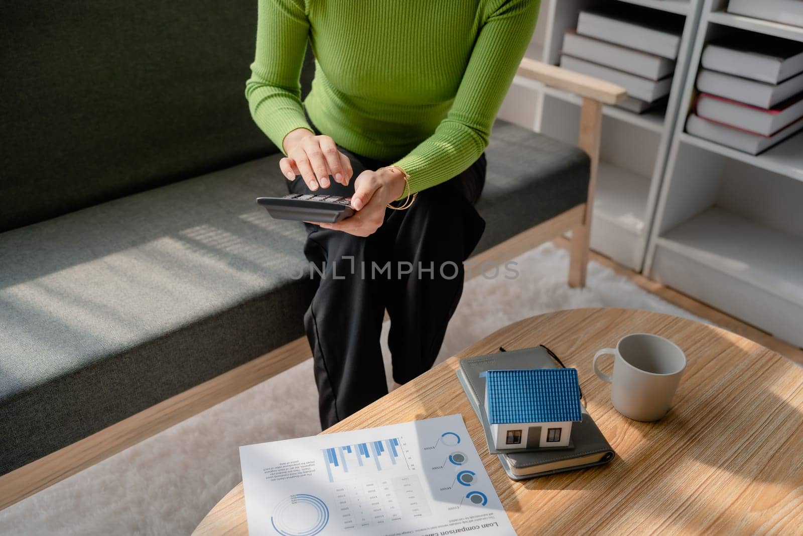 woman sitting on cozy sofa and planning and calculate expense and mortgage with calculator and home on desk, insurance and budget of residential, loan and residence, business and property concept