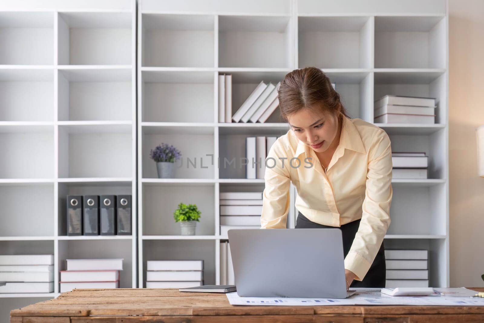 Excited business asian woman sitting at table with laptop and celebrating success..