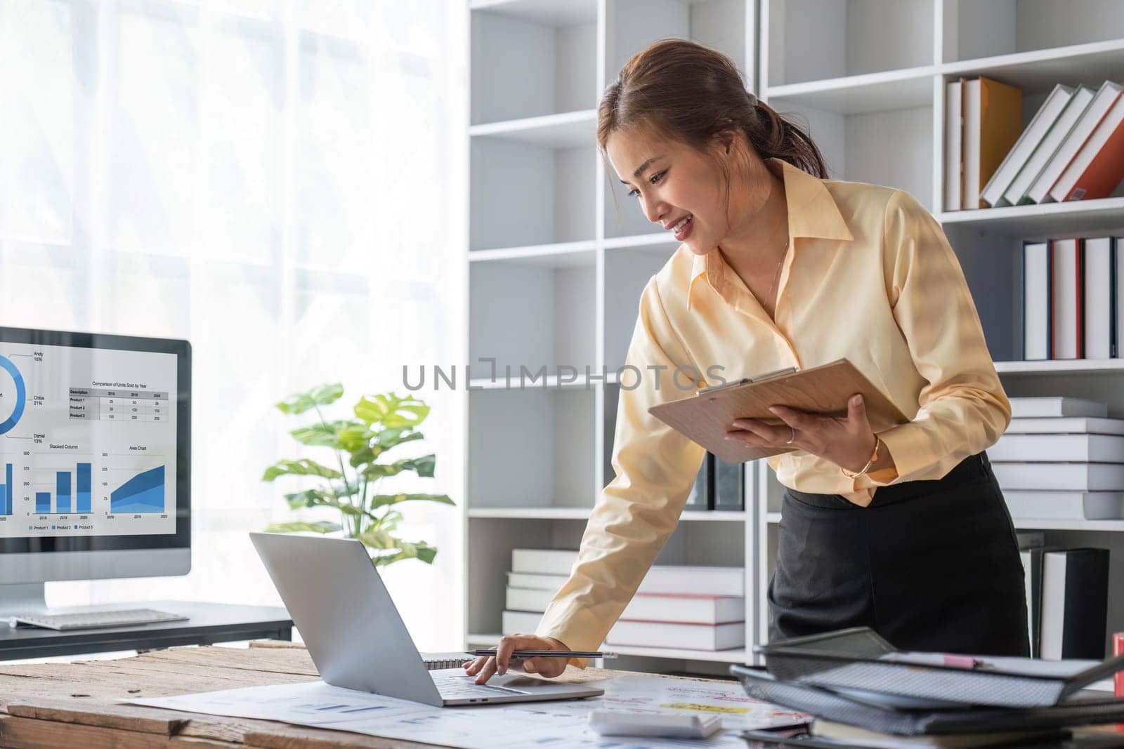 Excited business asian woman sitting at table with laptop and celebrating success..